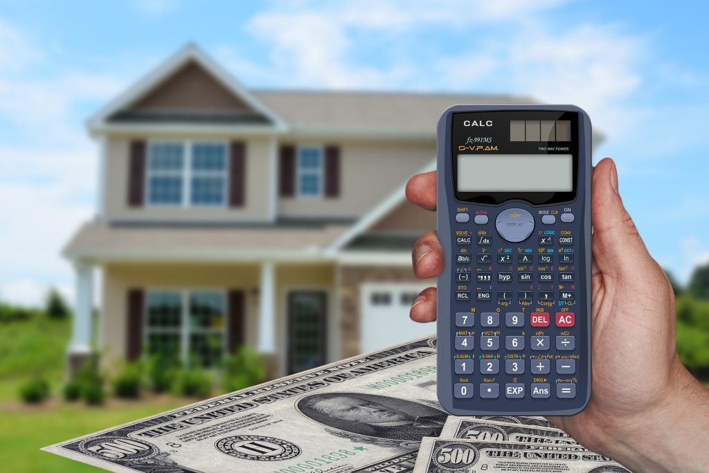 Calculator in hand with home and money in the background
